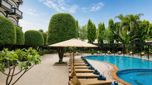 a resort pool with lounge chairs and an umbrella at The Heritage Courtyard in Siem Reap