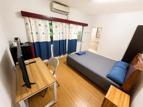 a bedroom with a bed and a desk with a computer at Comfortable Ensuite Room in Suva CBD in Suva