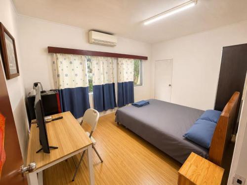 a bedroom with a bed and a desk with a television at Comfortable Ensuite Room in Suva CBD in Suva