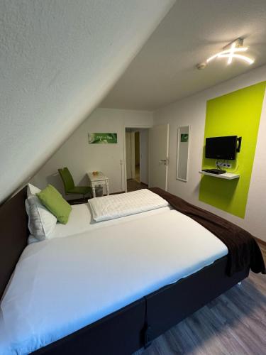a large white bed in a room with a green wall at ManusFaktur Waldcafé und Hotel in Nordhastedt