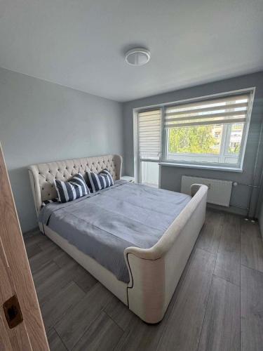 a bedroom with a large bed and a window at Geri Apartamentai in Naujoji Akmenė