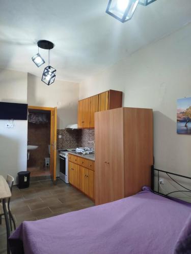 a bedroom with a purple bed and a kitchen at Mani GuestHouse in Kyparissos