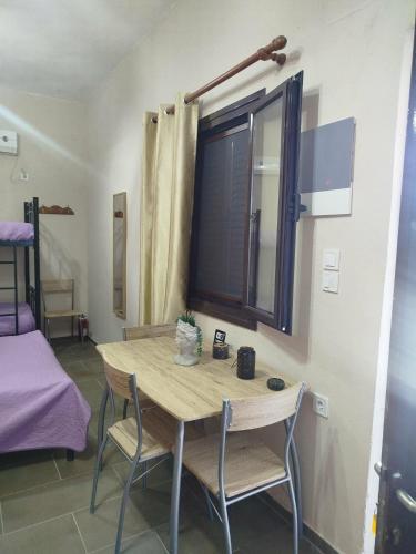 a table with two chairs and a window in a room at Mani GuestHouse in Kyparissos