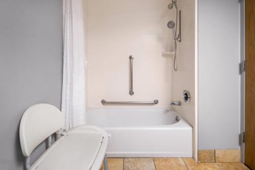 a white bathroom with a tub and a toilet at AmericInn by Wyndham Madison West in Madison