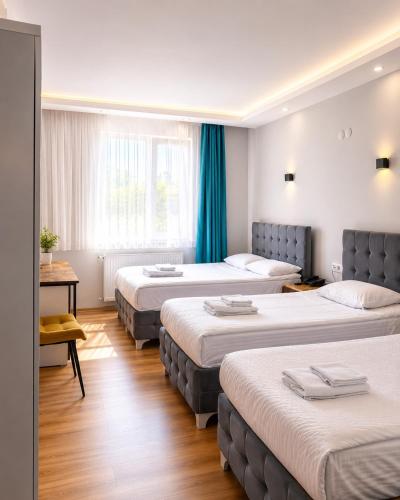 a hotel room with four beds with blue curtains at Mavi OTEL BOUTİQUE RESTAURANT in Mahmutlu