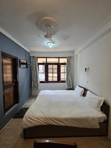 a bedroom with a large white bed with a window at City Star in Srinagar