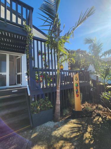 a house with a palm tree next to a fence at Darlene's Nest in Cable Bay