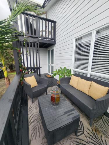 a patio with couches and a table and chairs at Darlene's Nest in Cable Bay