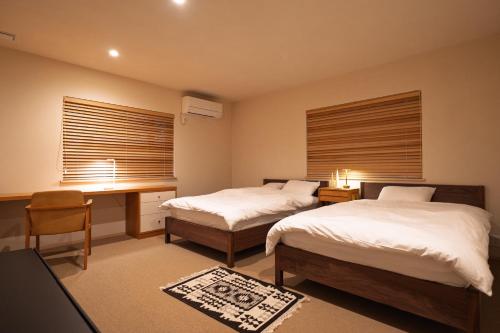 a bedroom with two beds and a desk and a desk at u10 -ユーテン- in Kakegawa