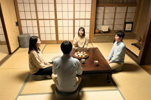 a group of people sitting around a table in a room at Jokan-en in Honjo