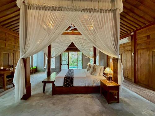 a bedroom with a canopy bed in a room at Sarini Joglo Villa by Manara in Blahbatu