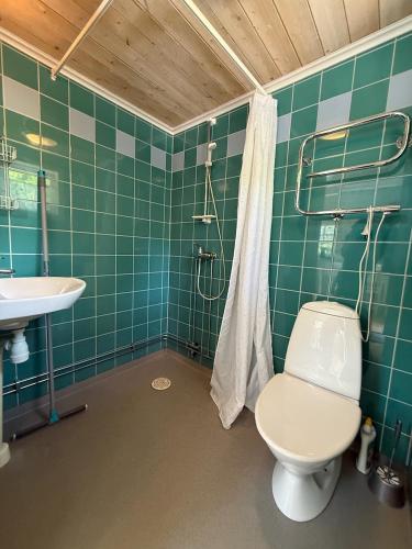 a green tiled bathroom with a toilet and a sink at Pensionat Lövängen, Ljugarn in Ljugarn