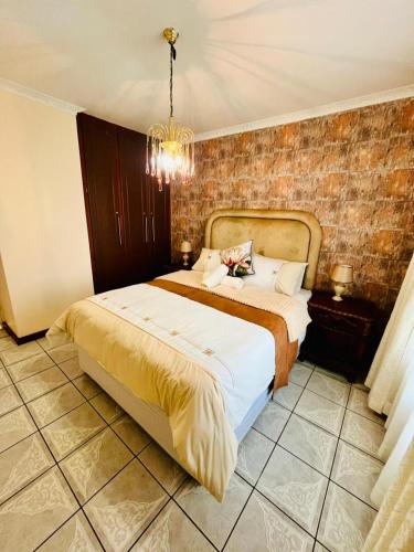 a bedroom with a large bed and a chandelier at Emangwaneni Guest House in Kloof