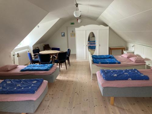 a room with four beds and a table and chairs at STF Vandrarhem Backåkra in Löderup