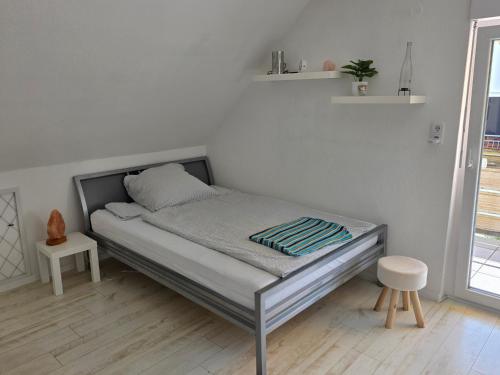 ein Bett in einem weißen Zimmer mit einem Bettgestell in der Unterkunft Studio Seeperle in Owingen