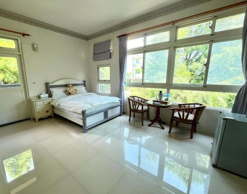 a bedroom with a bed and a table and windows at 花蓮統一的家民宿The home place in Ji'an