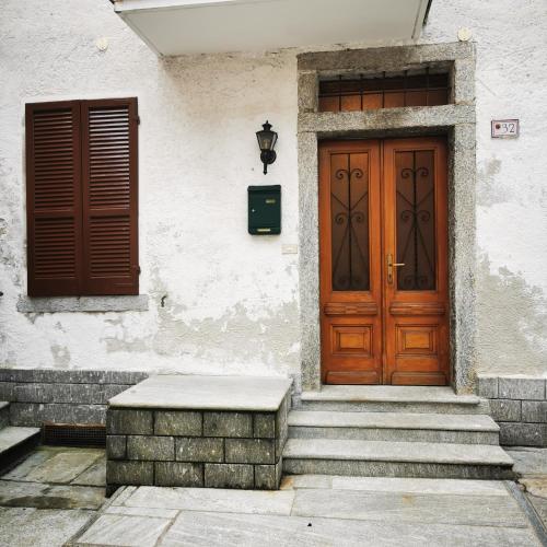 a building with a wooden door and stairs in front at Casa MEME' in Santa Maria Maggiore