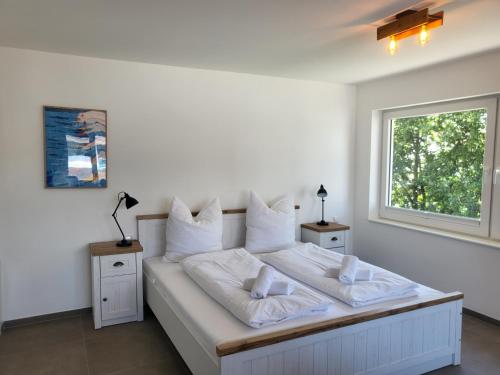 a bedroom with a bed with white sheets and a window at Haus Eintracht Appartment 3 in Sankt Peter-Ording