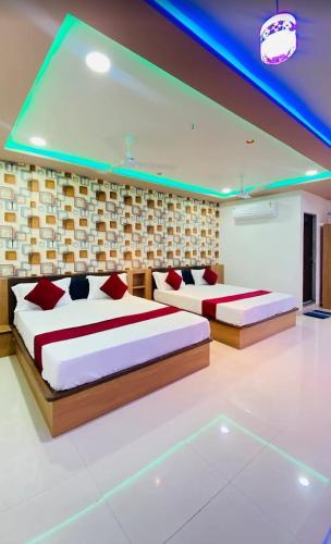 two beds in a large room with blue lights at Hotel New Vinay in Kapadvanj