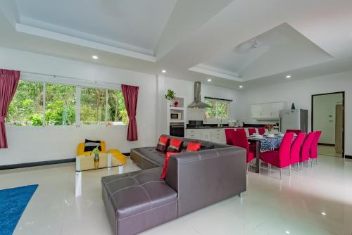 a living room with a couch and red chairs at Chalong - 4 Bedroom Private Pool Villa - Phuket in Chalong