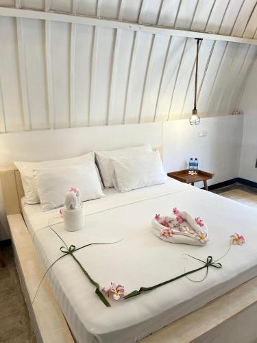 a white bed with two towels and flowers on it at TottyHouse Gili Trawangan in Gili Trawangan