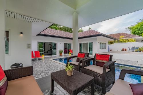 an outdoor patio with wicker furniture and a swimming pool at Chalong - 4 Bedroom Private Pool Villa - Phuket in Chalong