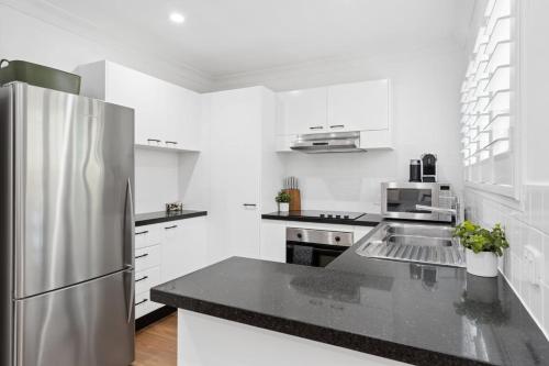 a white kitchen with a stainless steel refrigerator at Unit 6 Nirvana in Yaroomba