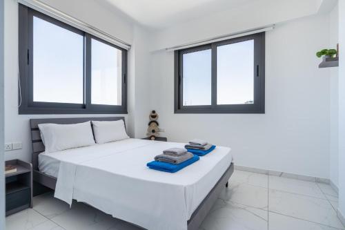 a bedroom with a white bed with two windows at Bright Stylish Flat With Balcony & Shared Pool in Scala