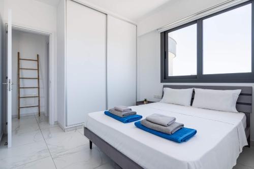 a bedroom with a large white bed with towels on it at Bright Stylish Flat With Balcony & Shared Pool in Scala
