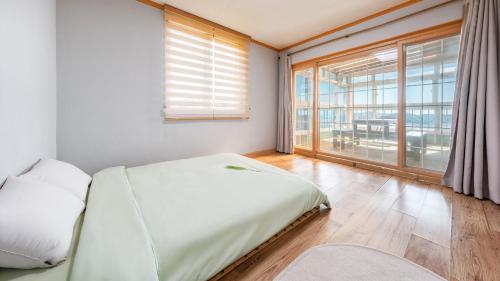 a bedroom with a bed and a large window at Yeongheungdo noeul&bada pension in Incheon