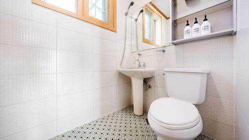a white bathroom with a toilet and a sink at Yeongheungdo noeul&bada pension in Incheon