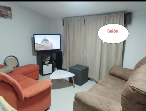 a living room with a couch and a tv with a bubble saying salon at Vivienda Turística Ático in Laxe