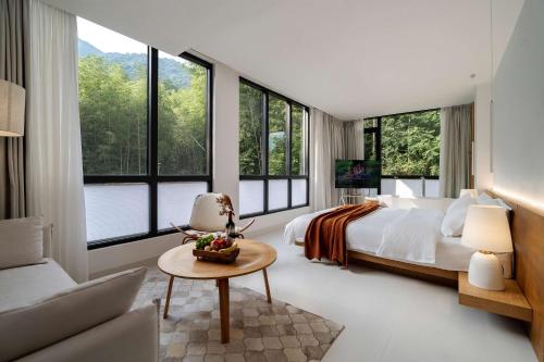 a bedroom with a bed and large windows at Congxi Creek Resort in Conghua