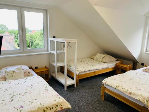 a attic room with two beds and two windows at M&M Marzeniowo in Chlebowo
