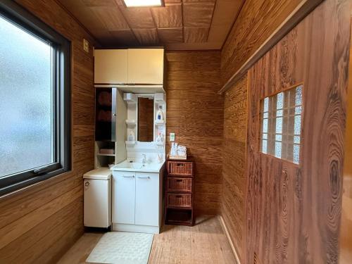 eine Küche mit weißem Kühlschrank und Holzwänden in der Unterkunft かんさんのお宿 in Fuji