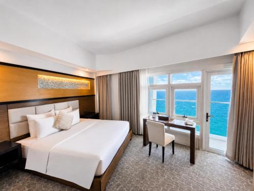 a hotel room with a large bed and a desk at Arterra Hotel and Resort in Mactan
