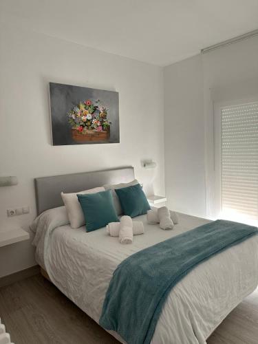 a white bedroom with a large bed with blue pillows at CASA MARUJA in Ávila