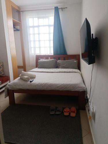 a bedroom with a bed with a television and shoes at Studio solace kitisuru in Nairobi