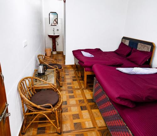 a room with two beds and a table and chairs at Hotel Padam Niwas in Ukhimath