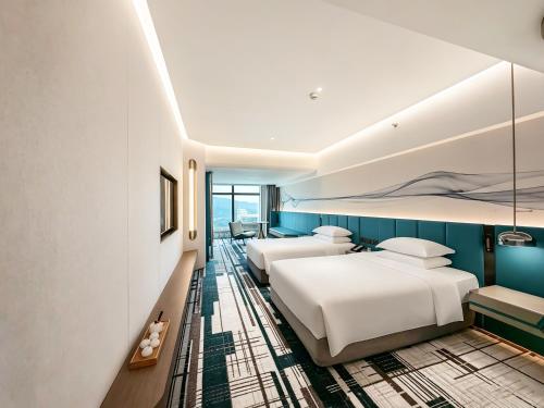 two beds in a hotel room with blue walls at Asia International Hotel Guangdong in Guangzhou