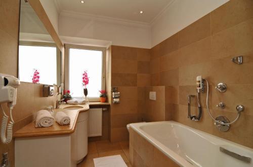 a large bathroom with a tub and a sink at DAD Vogelweiderhof Rooms in Salzburg