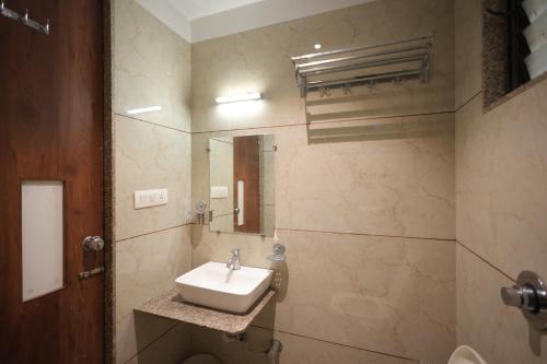 a bathroom with a sink and a mirror at Hotel Rangoli Dharampur in Dharampur