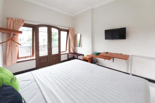 a white bedroom with a bed and a television at Urbanview Hotel Grand Palem near Alun Alun Batu in Songgoriti