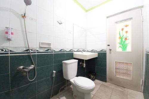 a bathroom with a toilet and a sink and a shower at Urbanview Hotel Grand Palem near Alun Alun Batu in Songgoriti