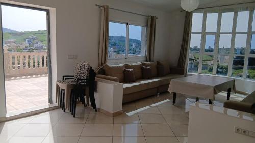 a living room with a couch and a table and windows at Mediterraneo House in Tangier