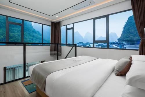 a hotel room with a bed and large windows at Ruqi Hotel in Yangshuo