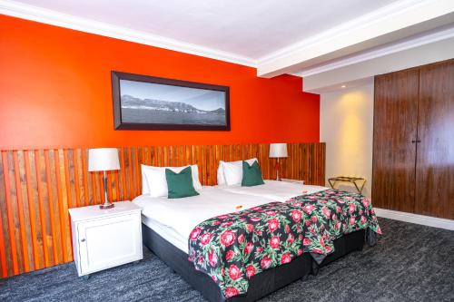 a bedroom with a large bed with an orange wall at Innscape Classic Hotel in Cape Town