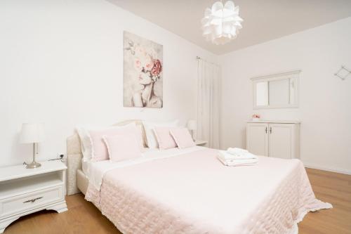 a white bedroom with a large white bed with pink pillows at Apartments Doris in Zadar