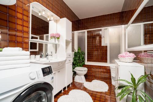 a white bathroom with a toilet and a sink at Apartments Doris in Zadar