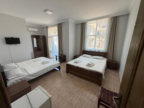 a hotel room with two beds and two windows at Hotel Like Mari in P'ichvnari
